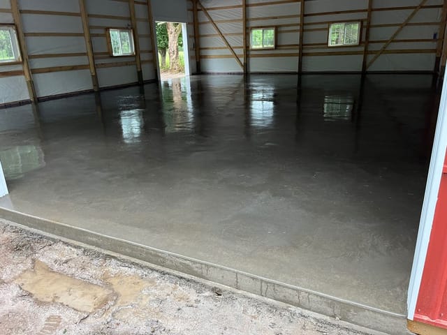 Interior of a large, empty garage or pole barn with a smooth, freshly poured concrete floor in St. Michael, MN.